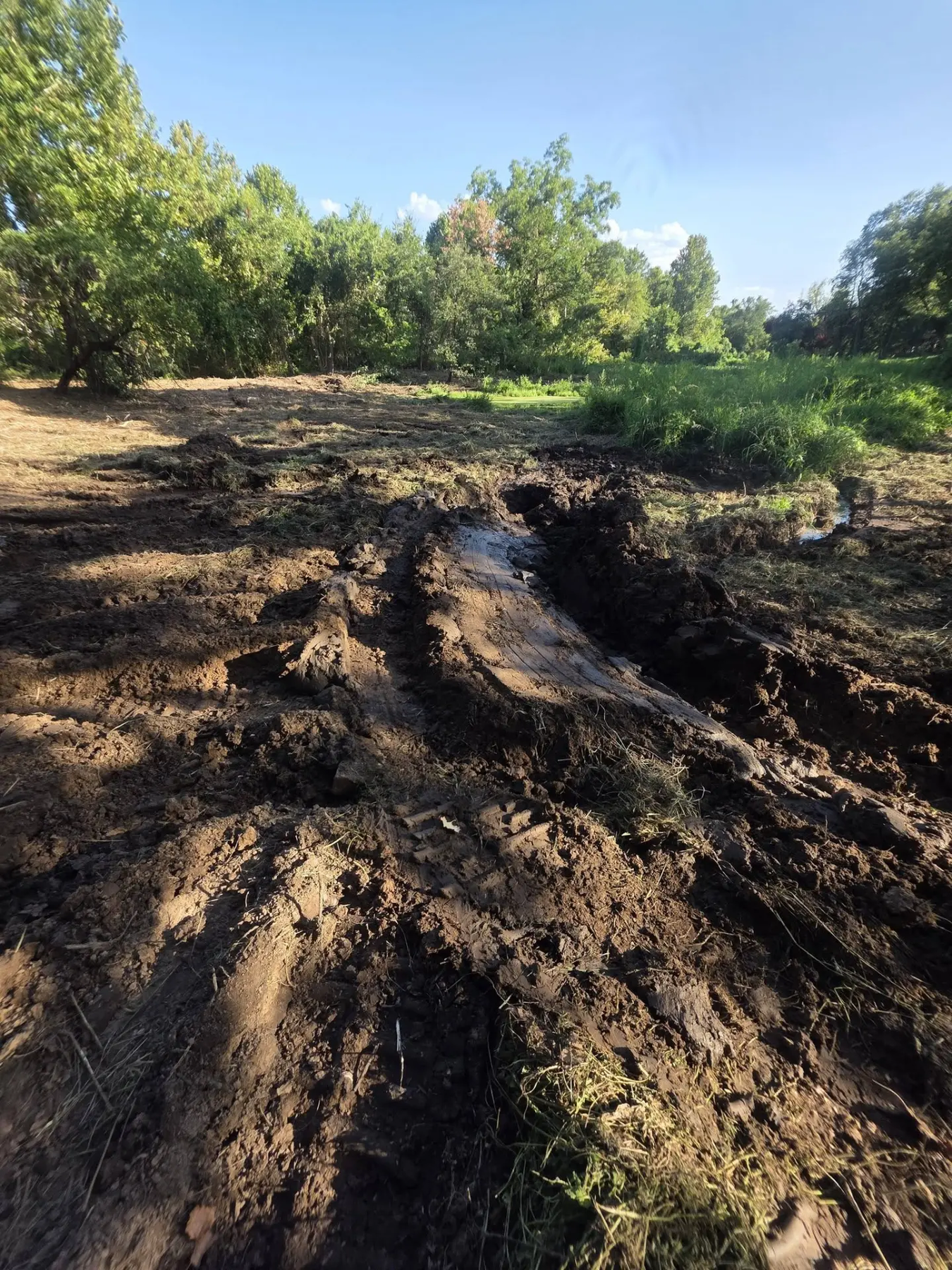 Freshly torn earth and track marks across a cleared field