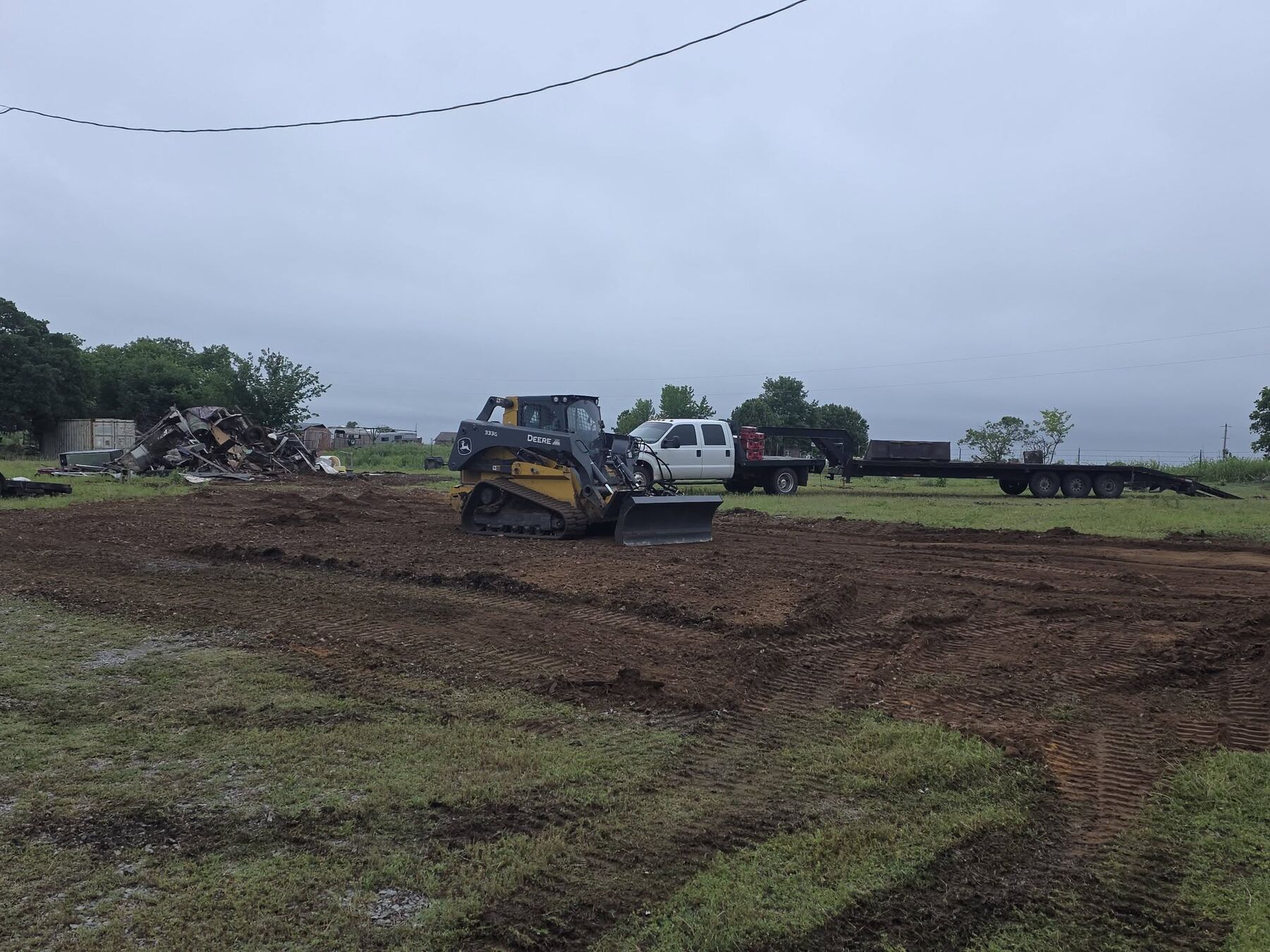 Track loader grading a muddy lot during dirt work near Cleveland, Oklahoma