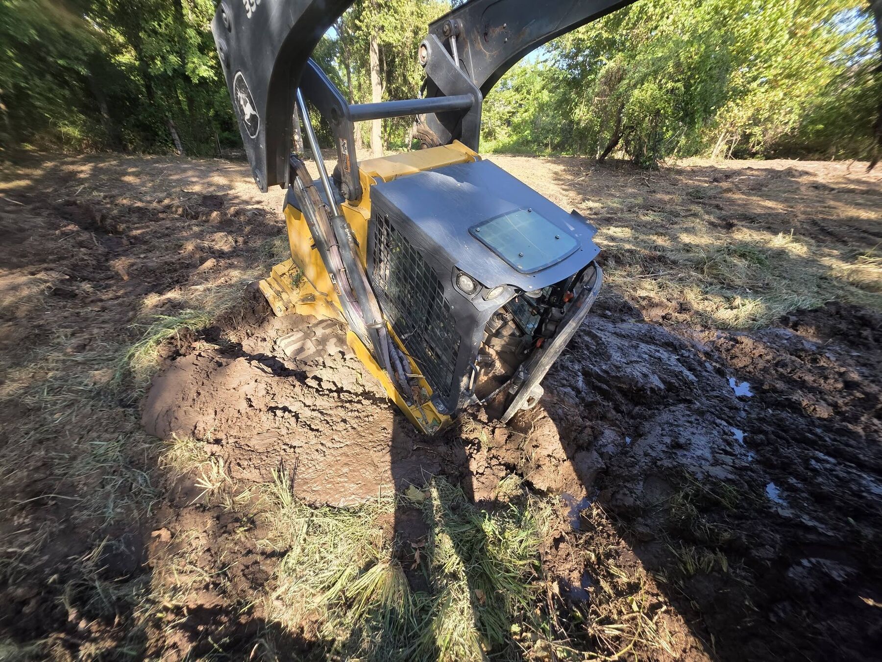 Skid steer grapple lifting a large log during land clearing